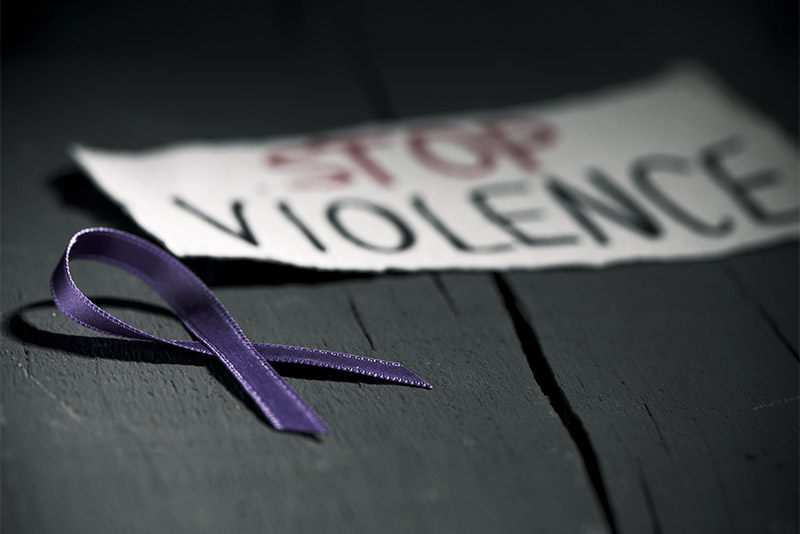 Purple ribbon next to paper with 'Stop Violence' written on it